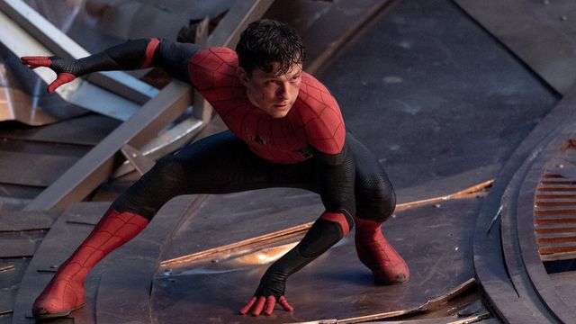 Peter Parker, unmasked in his black and red Spider-Man costume, crouches as he prepares to spring into action in Spider-Man: No Way Home