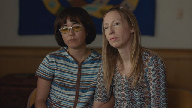 Maya Erskine and Anna Konkle playing tween versions of themselves in Pen15. The two sit next to each other, dressed like middle schoolers.