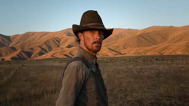 Benedict Cumberbatch in a cowboy hat, standing in a field in The Power of the Dog